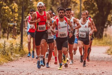 Group of male marathon runners competing on an outdoor trail surrounded by trees.