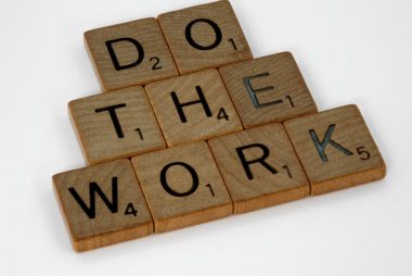 Creative arrangement of Scrabble tiles spelling 'Do the Work' on a white background.